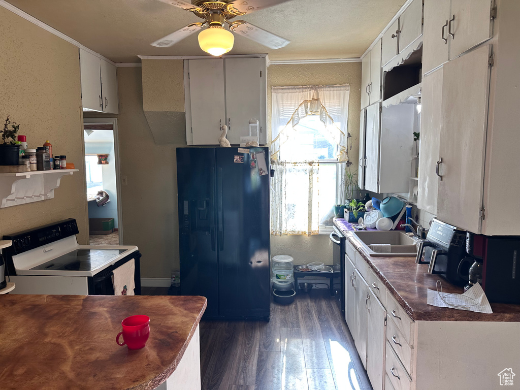 Kitchen with black fridge, electric stove, a sink, dark wood-type flooring, and ornamental molding