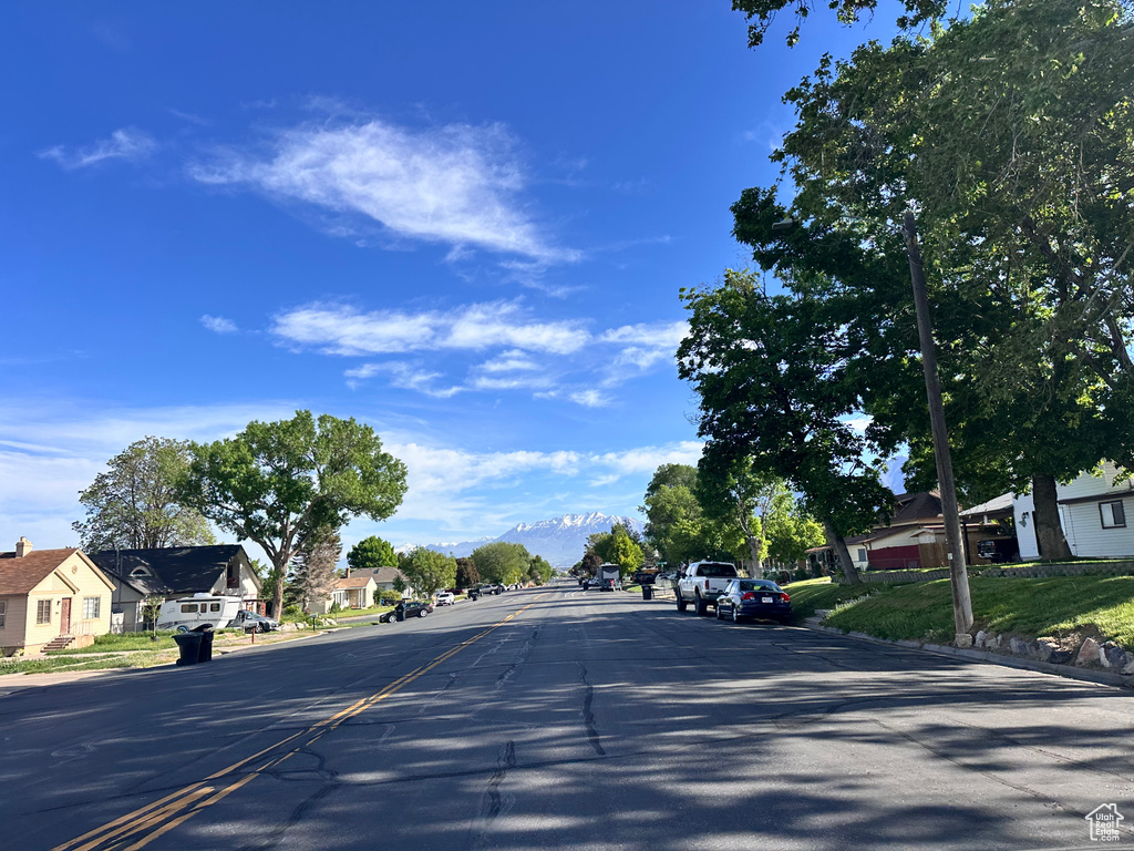 View of asphalt road with a residential view, curbs, and sidewalks