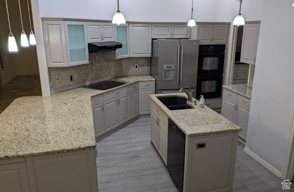 Kitchen featuring black appliances, a sink, under cabinet range hood, backsplash, and light wood-type flooring
