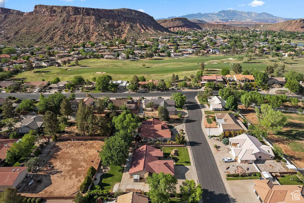 Aerial view of property and surrounding area featuring nearby suburban area, mountains, and a golf club