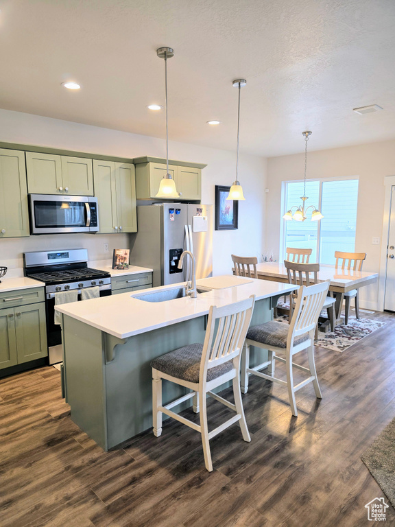 Kitchen featuring stainless steel appliances, green cabinets, a breakfast bar area, dark wood-style flooring, and recessed lighting