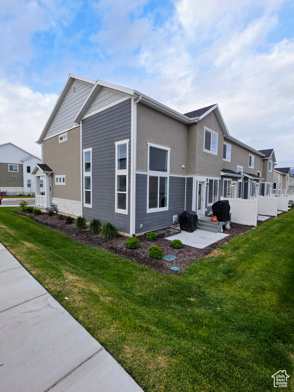 Back of house featuring a patio, a lawn, stucco siding, and entry steps