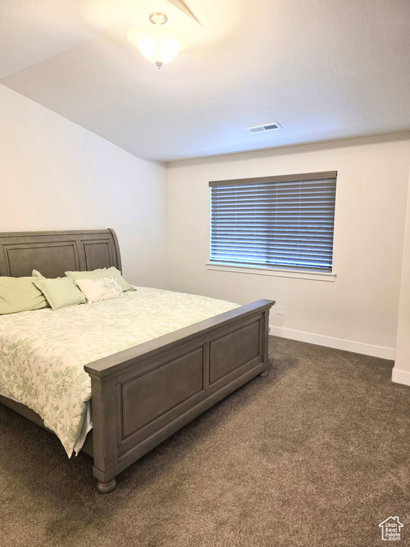 Bedroom with dark carpet and baseboards