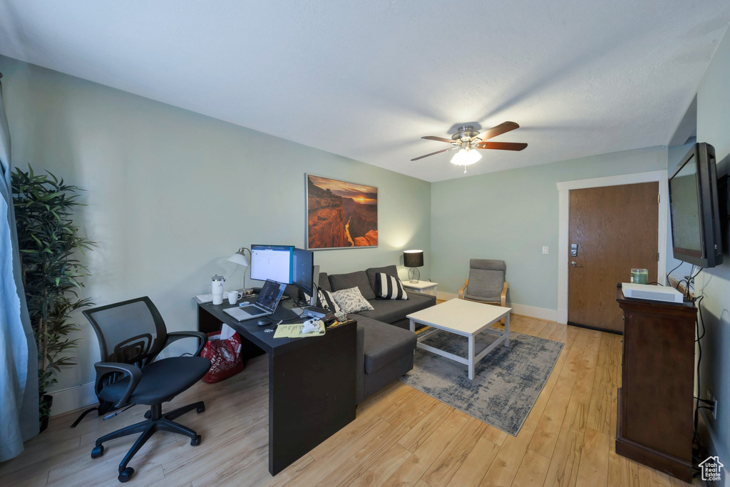 Office space with a ceiling fan, light wood-style floors, and baseboards