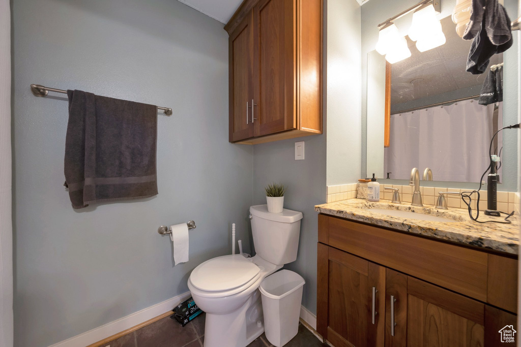 Bathroom with toilet, baseboards, vanity, tile patterned flooring, and a shower with curtain
