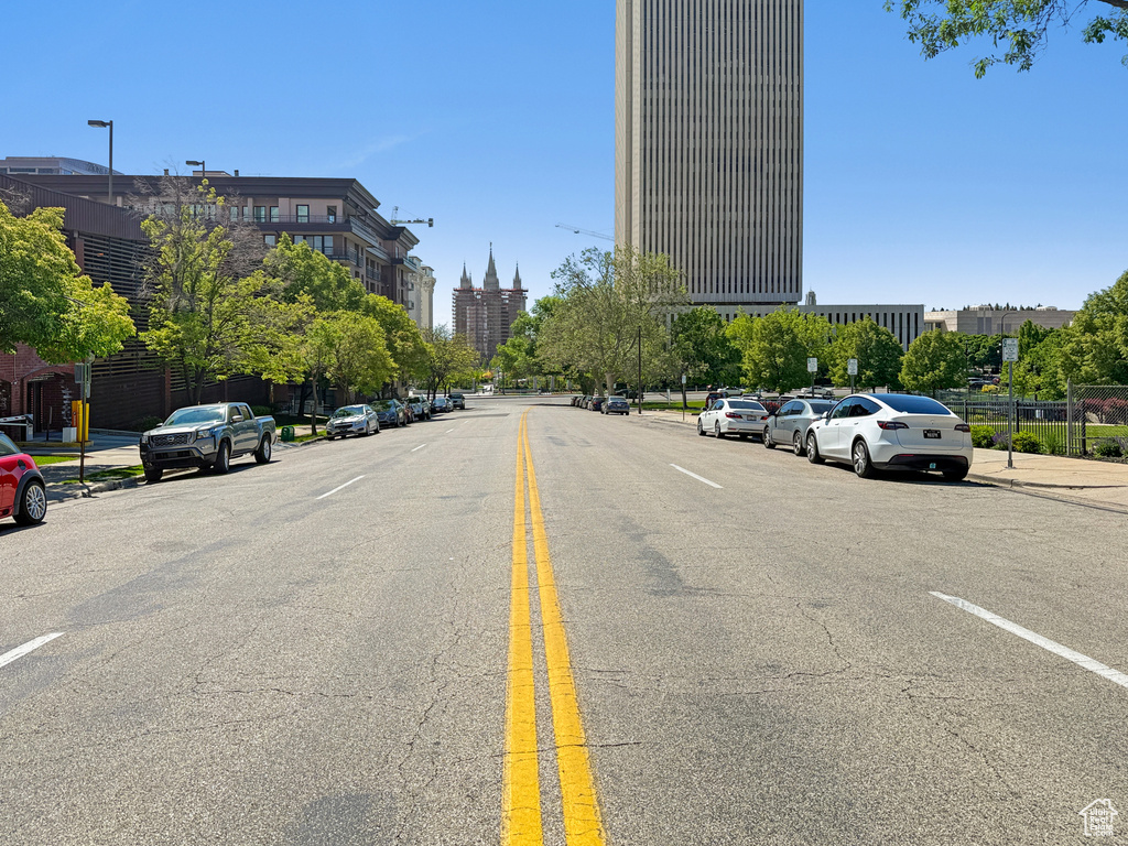 View of asphalt street featuring street lights, curbs, and sidewalks