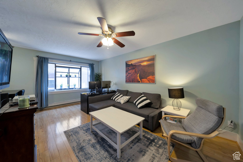 Living area featuring a ceiling fan, wood-type flooring, and baseboards