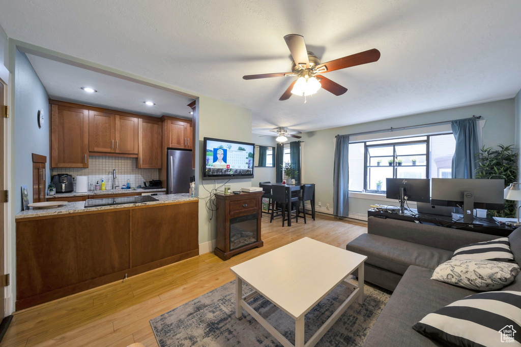Living room featuring light wood finished floors, a ceiling fan, recessed lighting, and baseboards