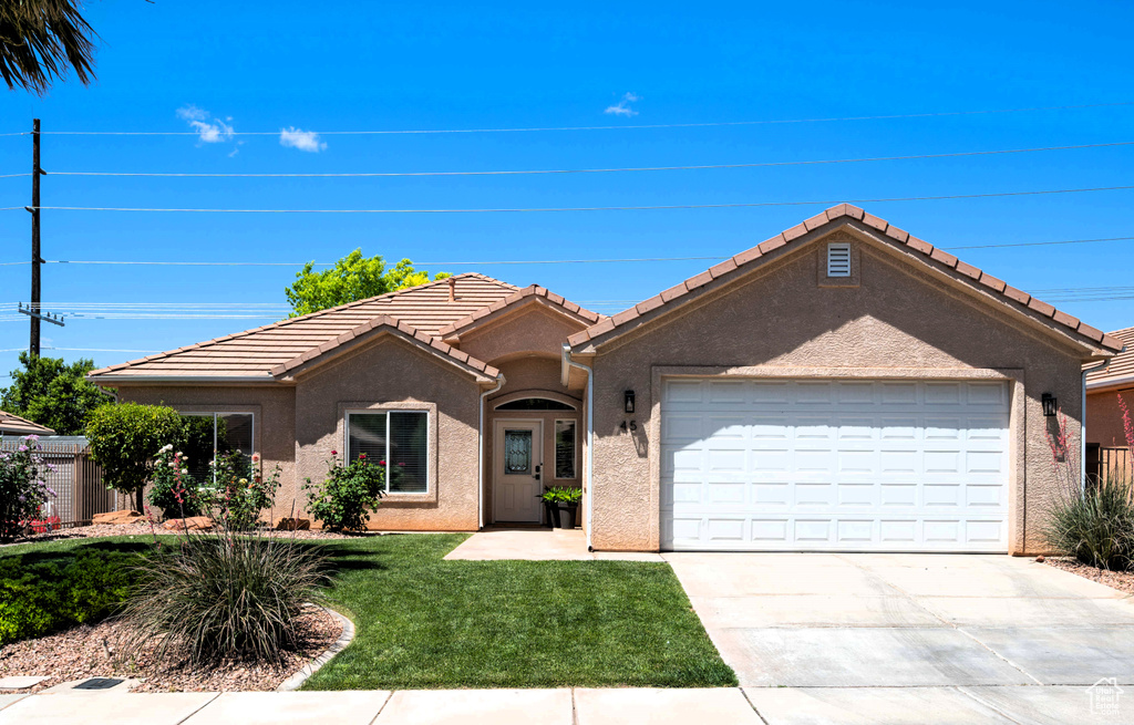 Ranch-style home with a garage, a front lawn, concrete driveway, stucco siding, and a tiled roof