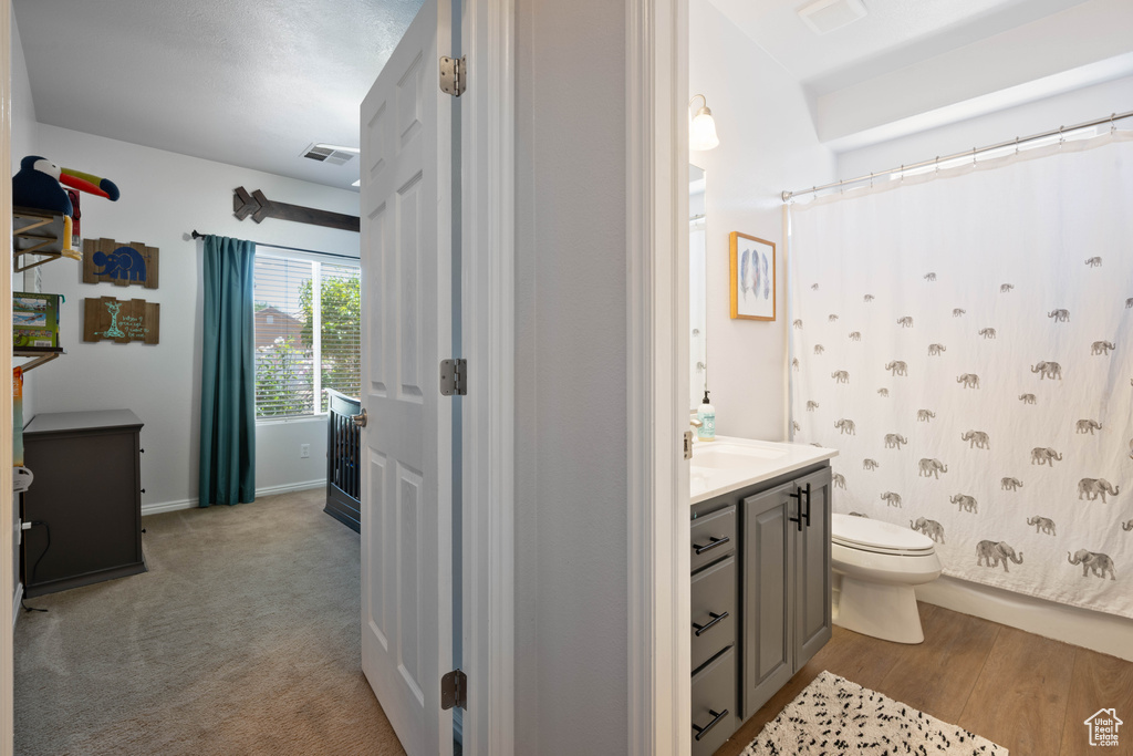 Full bathroom featuring toilet, vanity, a shower with curtain, and baseboards