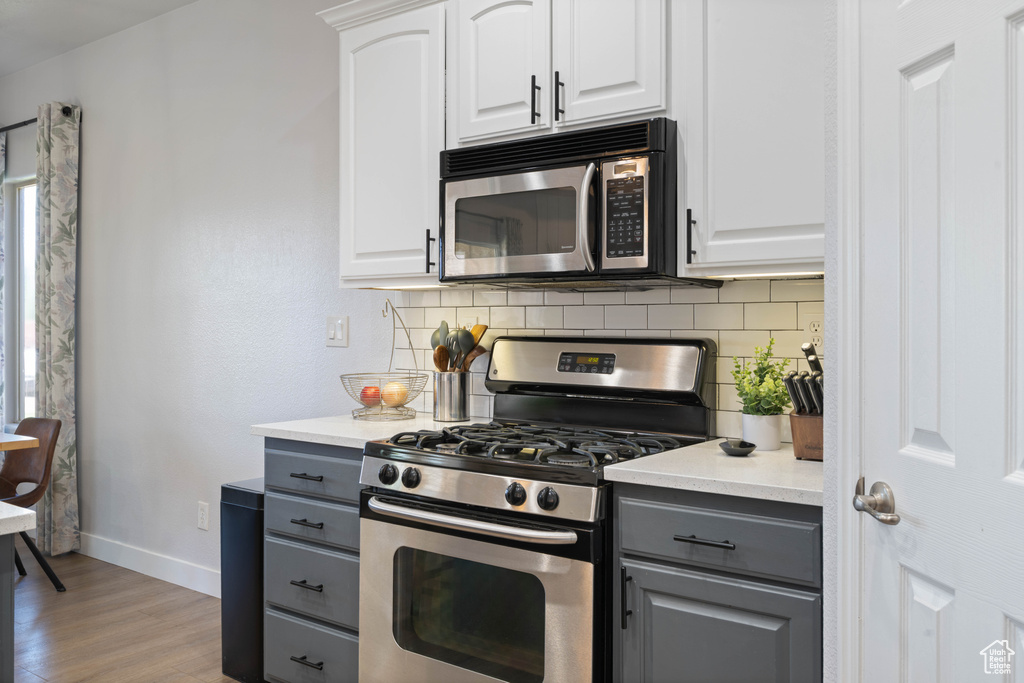 Kitchen with stainless steel appliances, gray cabinetry, baseboards, and tasteful backsplash
