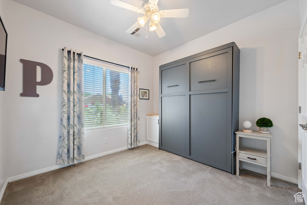 Unfurnished bedroom featuring light carpet, baseboards, and ceiling fan