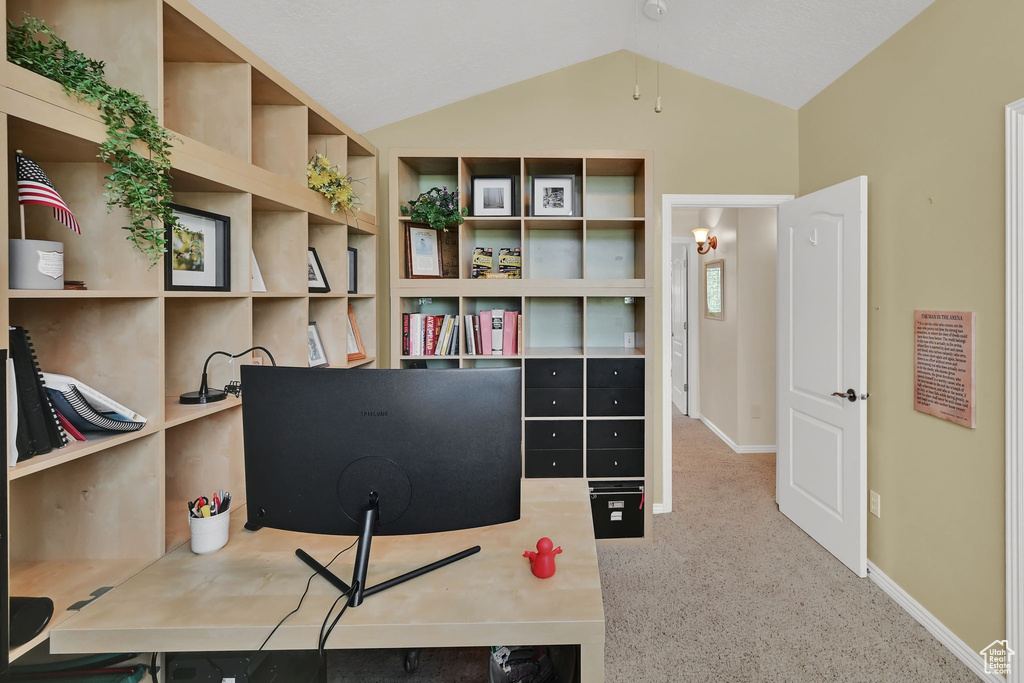 Carpeted home office with vaulted ceiling and baseboards