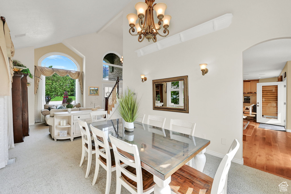 Dining space featuring arched walkways, stairs, a chandelier, high vaulted ceiling, and baseboards
