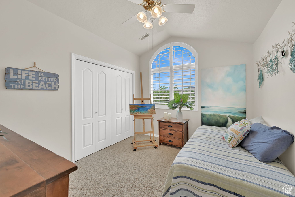 Carpeted bedroom with lofted ceiling, a closet, and a ceiling fan