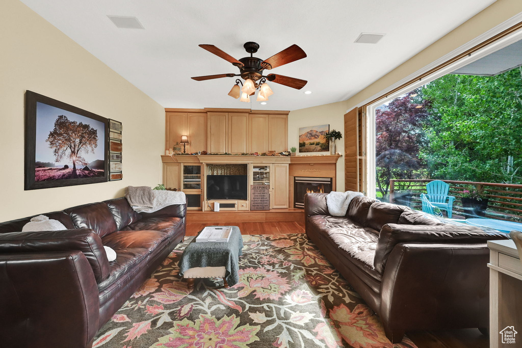 Living room featuring a ceiling fan, wood finished floors, and a glass covered fireplace