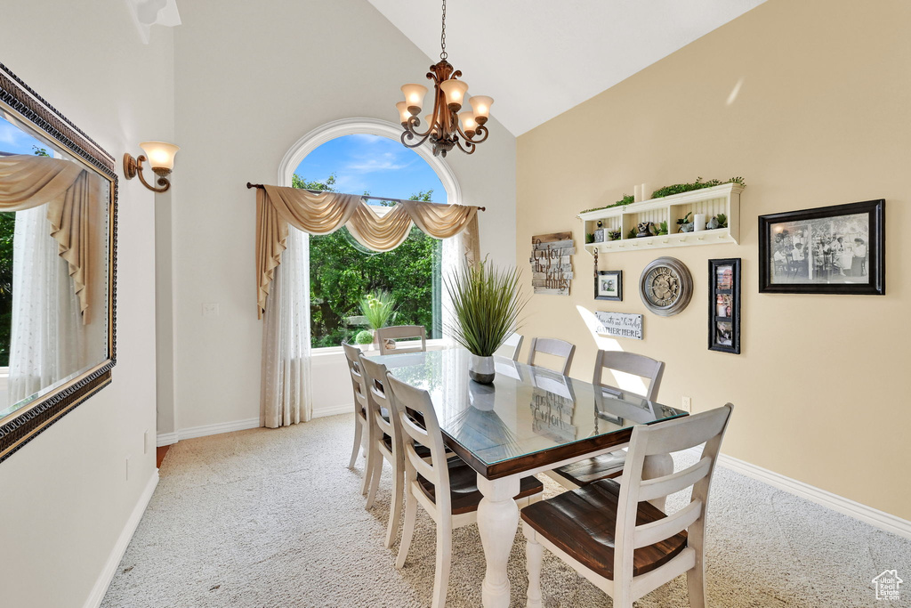 Dining space featuring high vaulted ceiling, baseboards, a chandelier, and carpet