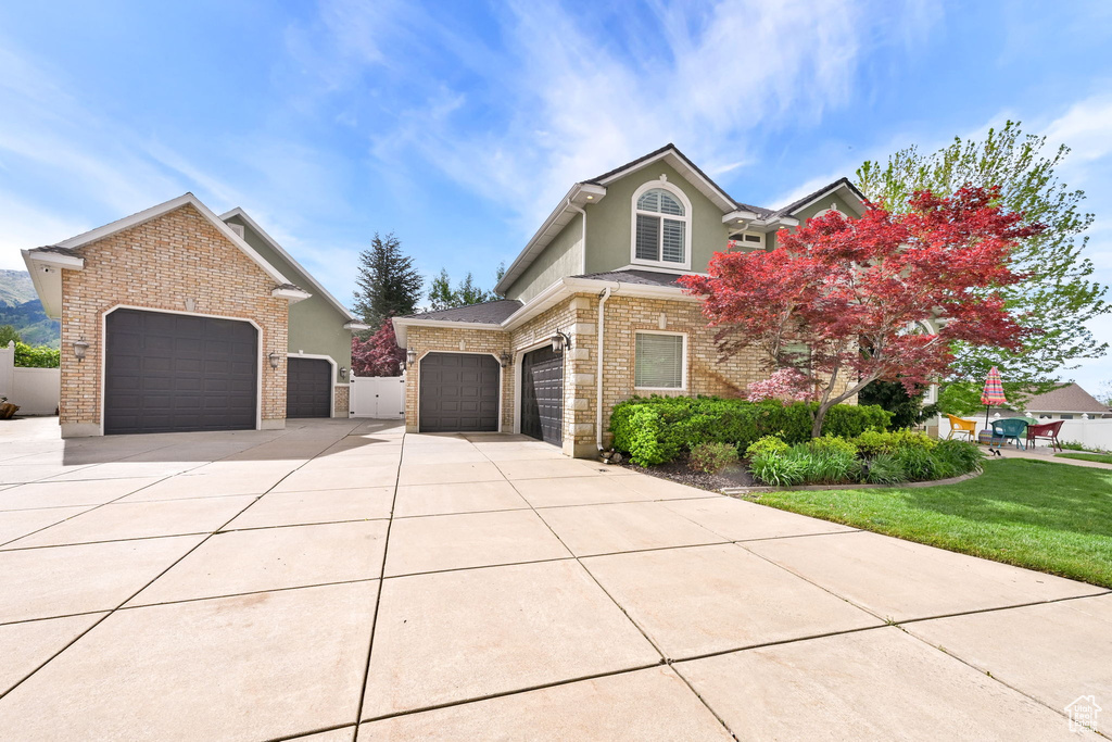 View of front of property with concrete driveway, an attached garage, brick siding, a front yard, and stucco siding