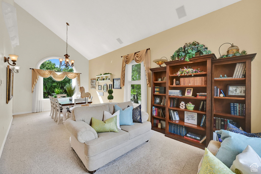 Carpeted living area with a chandelier, high vaulted ceiling, and baseboards