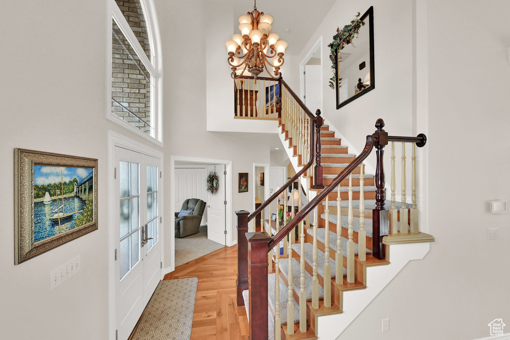 Foyer entrance with a high ceiling, a chandelier, stairs, and baseboards