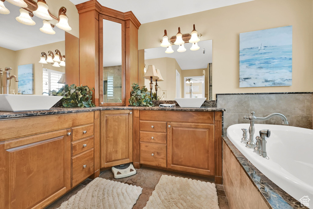 Bathroom with a bath, double vanity, and a chandelier