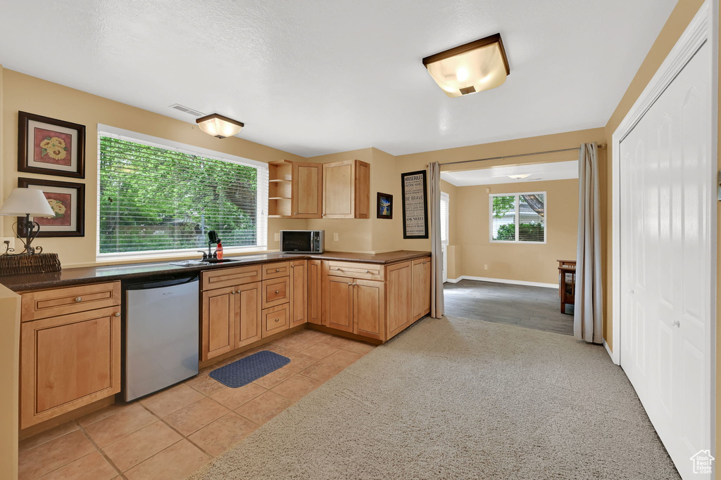 Kitchen featuring dishwasher, stainless steel microwave, open shelves, a sink, and light tile patterned floors