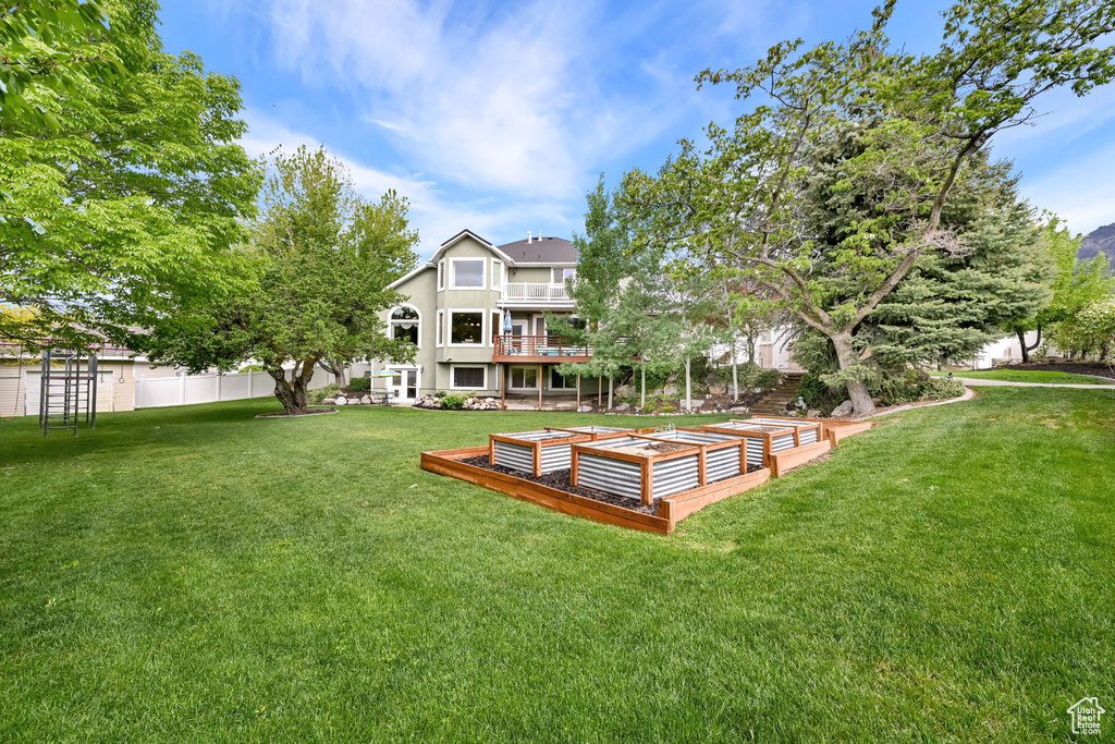 Back of house with a garden and a balcony
