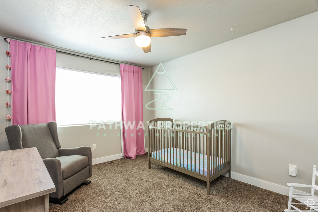 Bedroom with carpet, a nursery area, baseboards, and ceiling fan