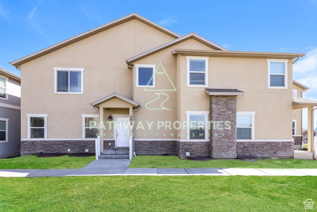 Multi unit property with stone siding, stucco siding, and a front lawn