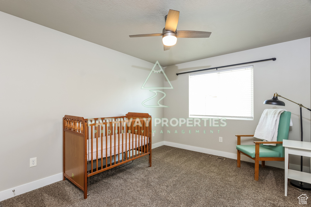 Bedroom featuring carpet flooring, baseboards, a crib, and a ceiling fan
