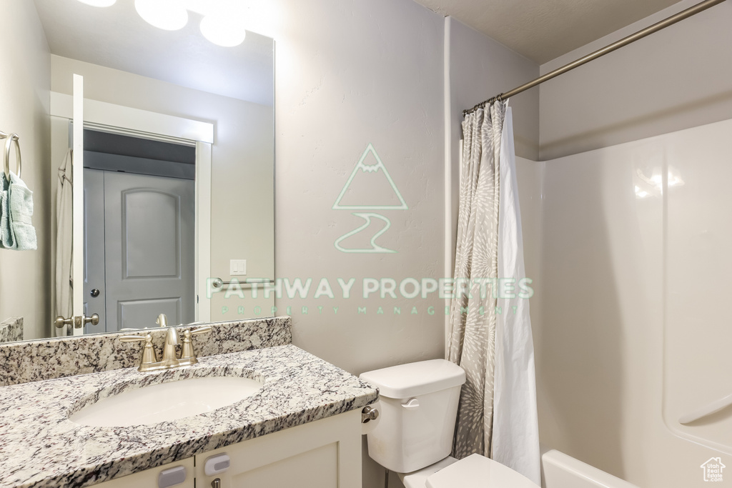 Bathroom with toilet, vanity, and curtained shower