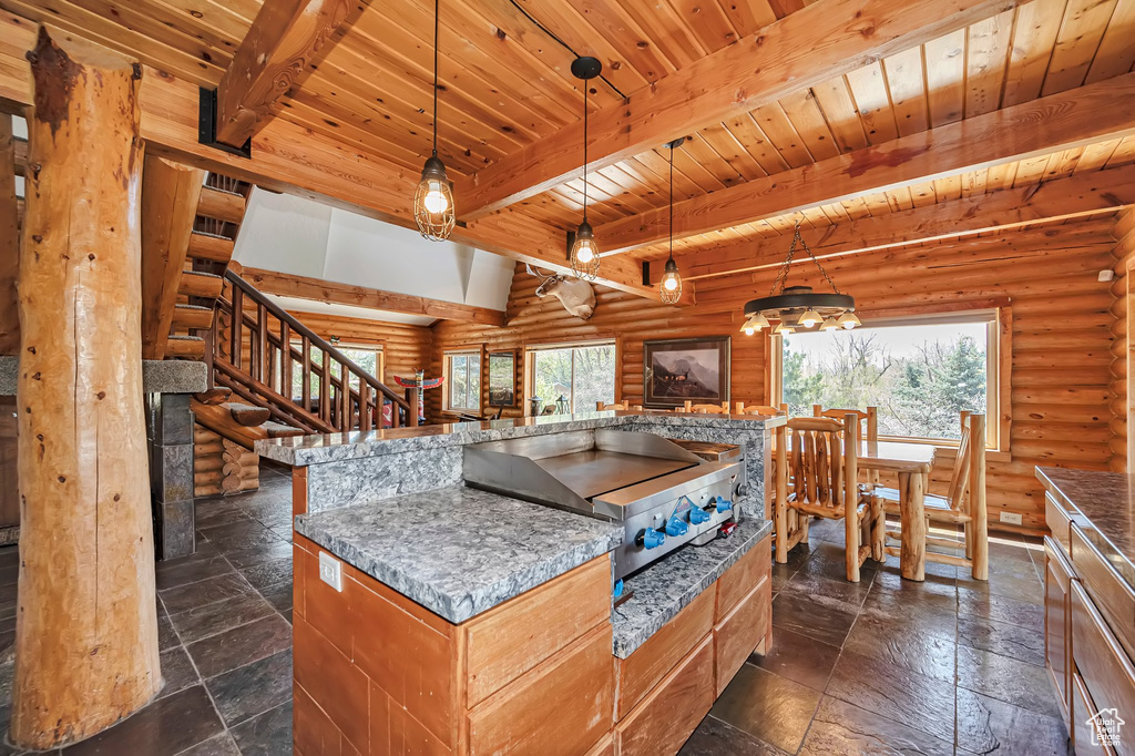 Kitchen featuring rustic walls, beamed ceiling, wooden ceiling, stone tile floors, and open floor plan