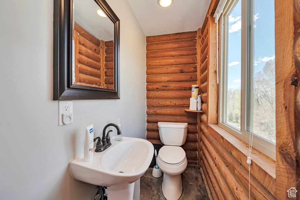 Half bathroom with rustic walls, a sink, and toilet