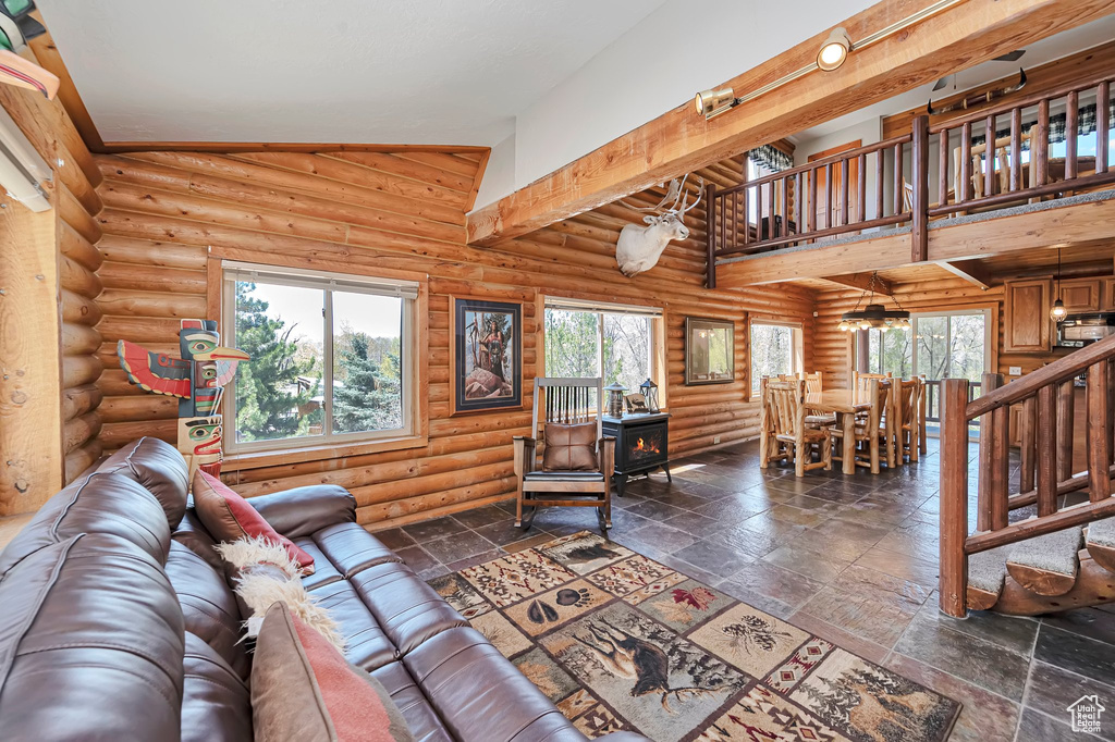 Living area with a wood stove, log walls, and stone tile floors