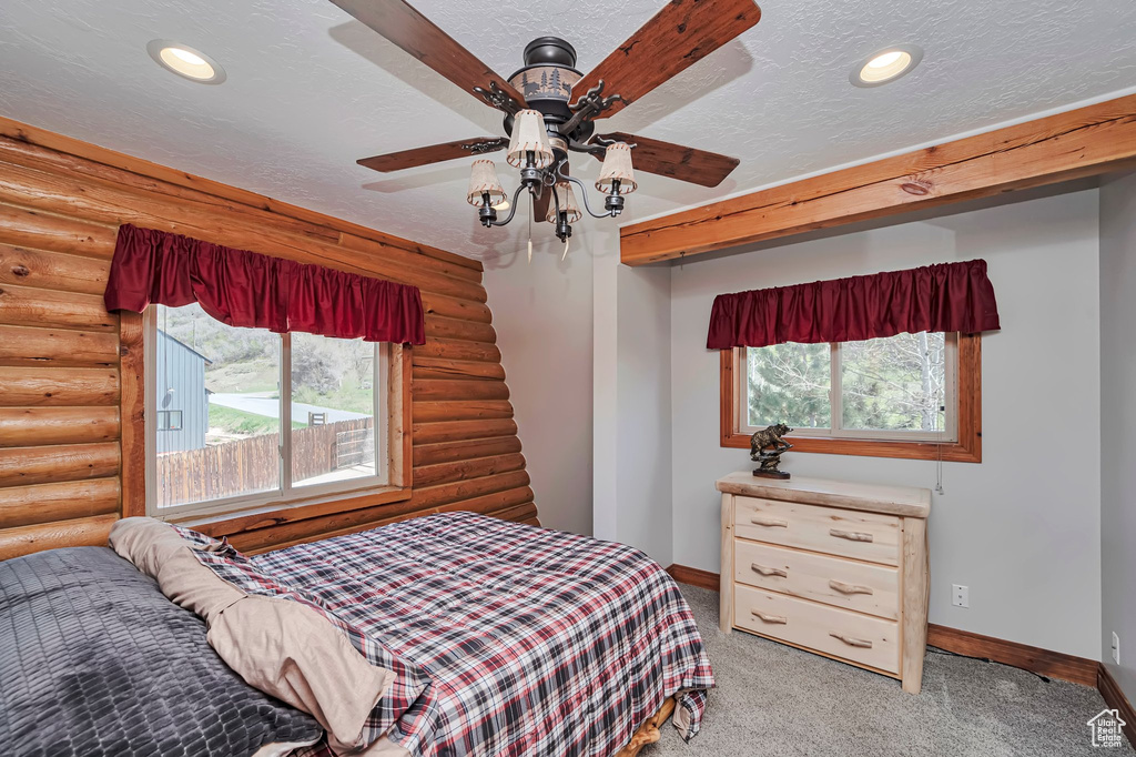 Bedroom with log walls, baseboards, light colored carpet, a textured ceiling, and recessed lighting