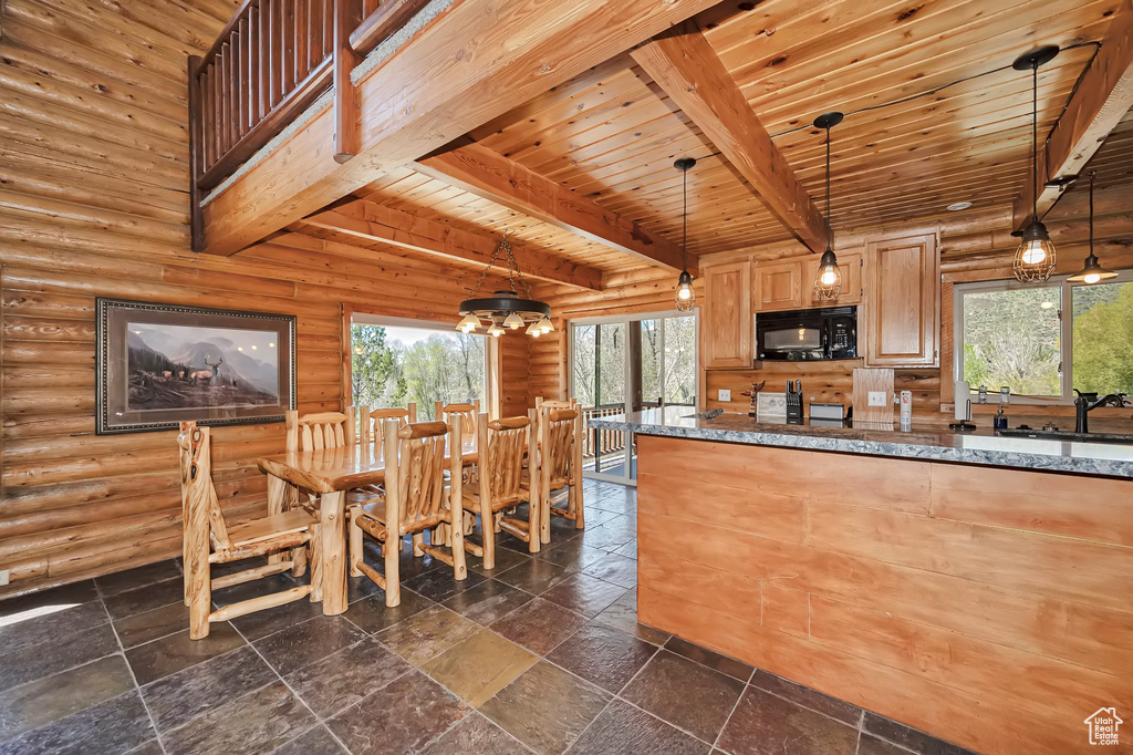 Kitchen featuring black microwave, beam ceiling, wooden ceiling, rustic walls, and dark stone countertops