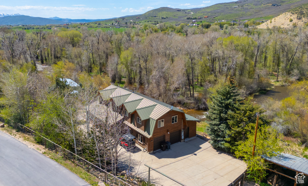 View of subject property featuring a mountain backdrop and a forest