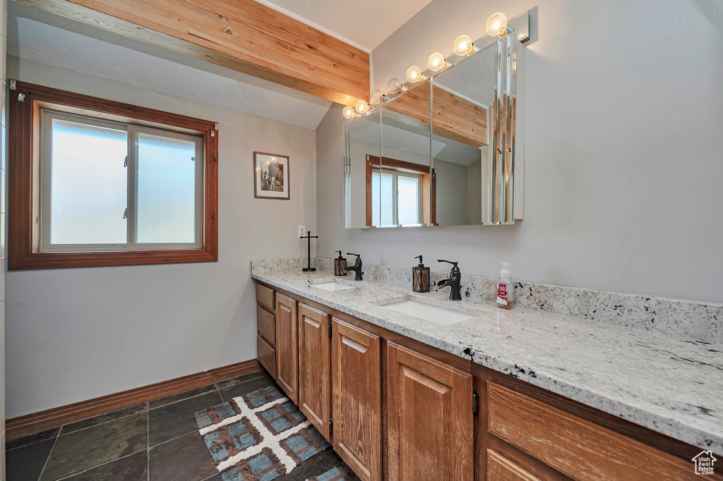 Full bathroom with baseboards, plenty of natural light, and double vanity