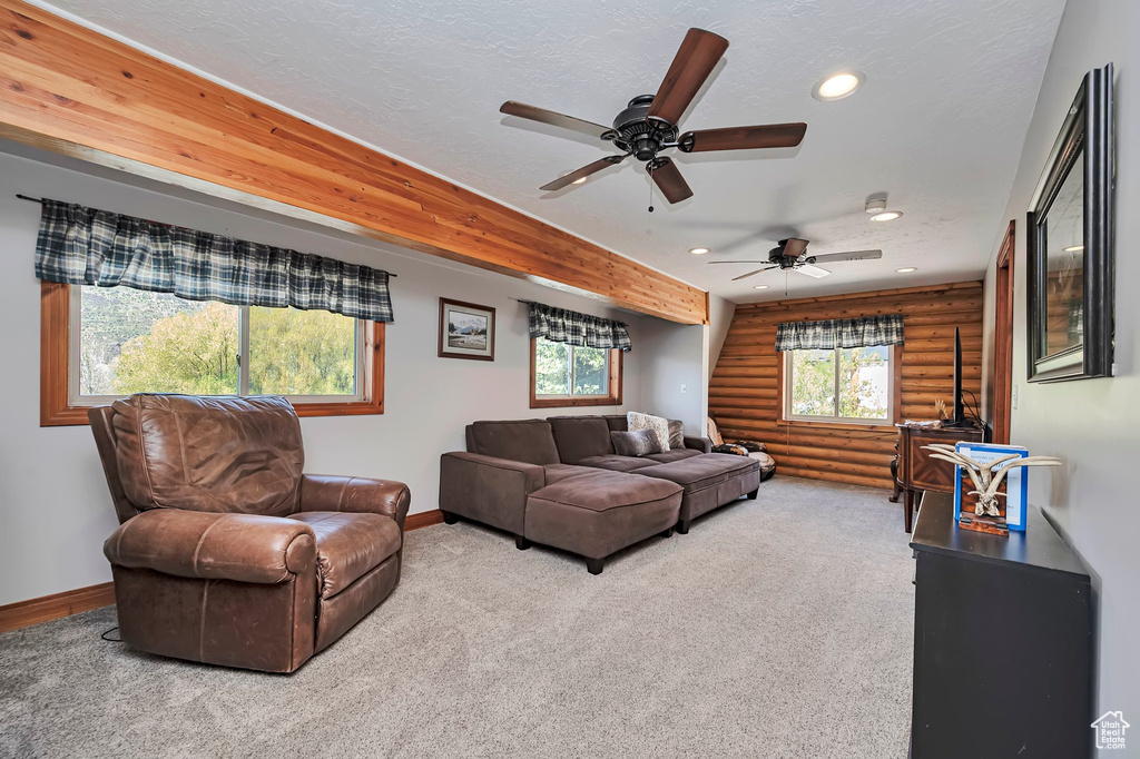 Carpeted living room with log walls, recessed lighting, baseboards, a ceiling fan, and a textured ceiling