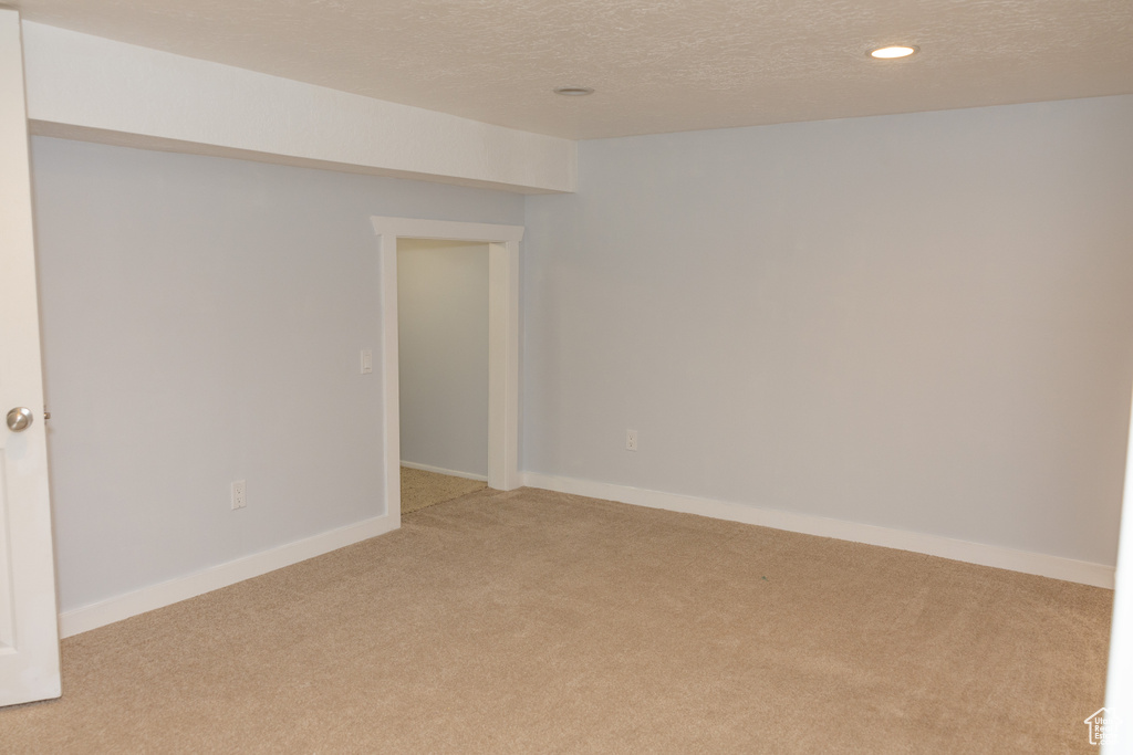 Spare room featuring light carpet, a textured ceiling, recessed lighting, and baseboards