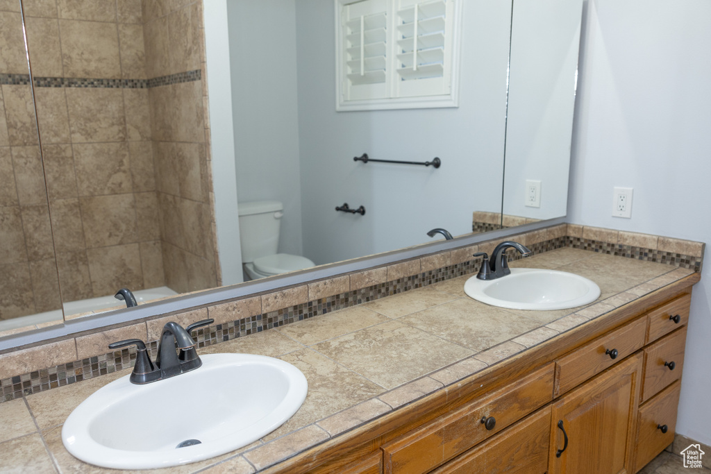 Full bathroom with double vanity, toilet, a bathtub, tasteful backsplash, and a shower