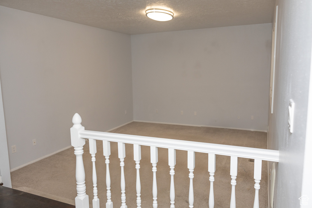 Stairway featuring carpet, a textured ceiling, and baseboards