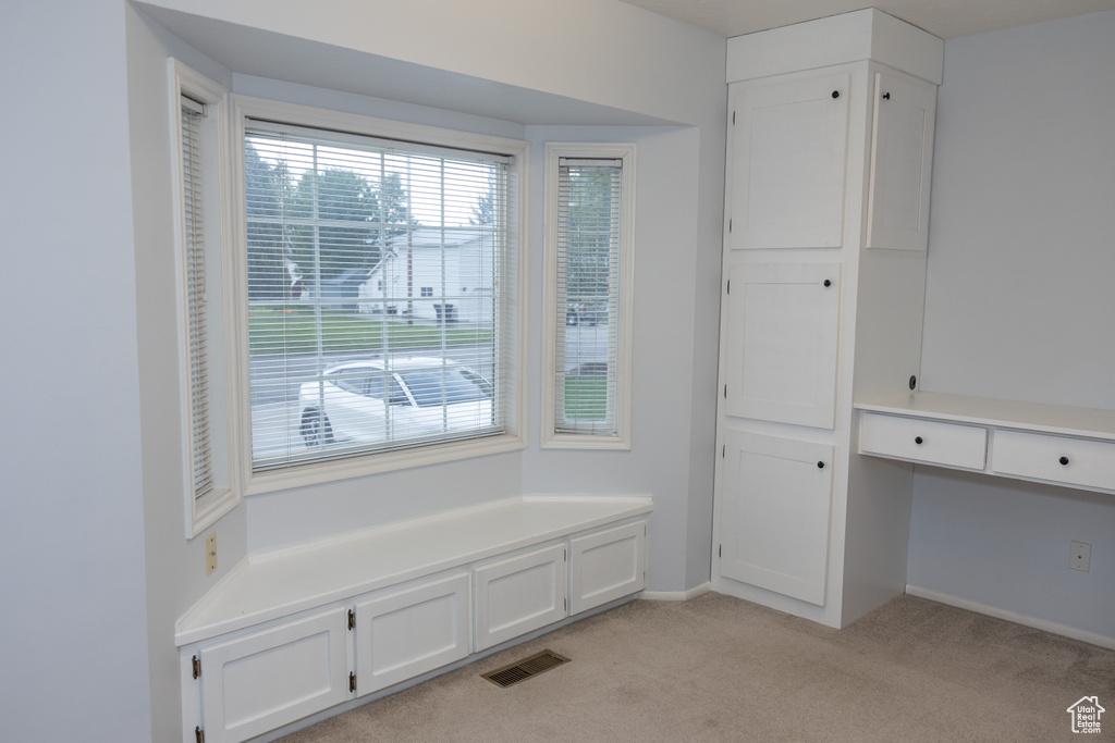 Unfurnished dining area featuring light carpet and baseboards