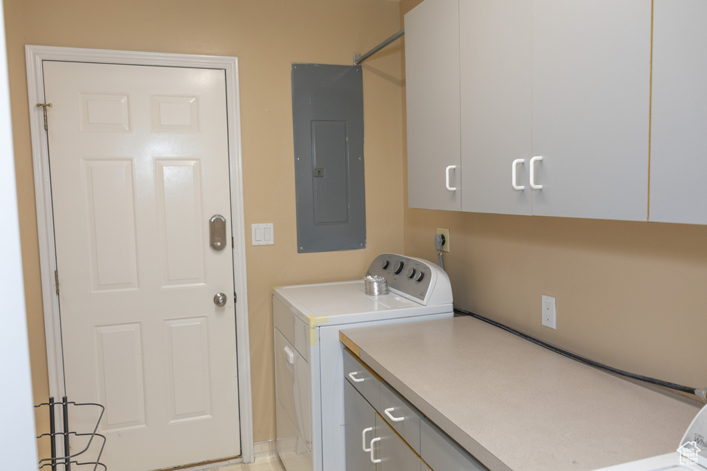 Laundry area featuring electric panel, washer and dryer, and cabinet space