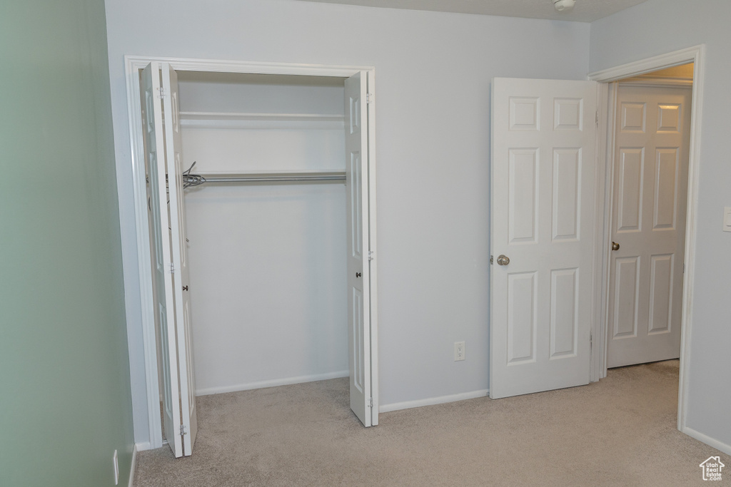 Unfurnished bedroom with carpet, a closet, and baseboards
