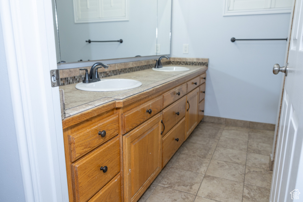 Full bath with double vanity, baseboards, and tile patterned floors