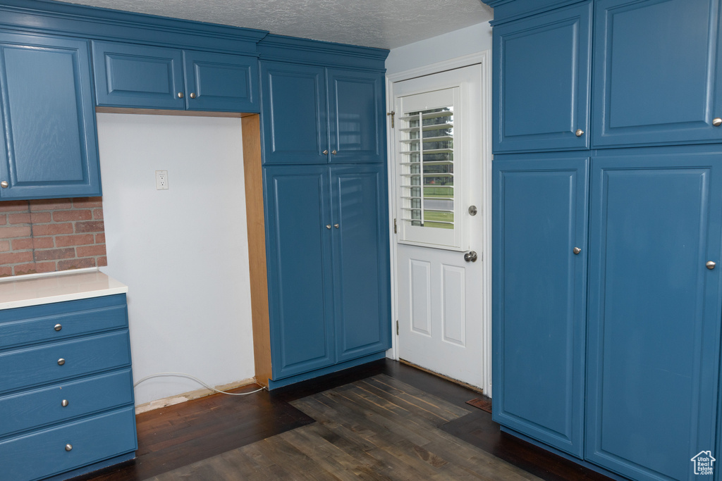 Kitchen with blue cabinets, decorative backsplash, light countertops, dark wood finished floors, and a textured ceiling