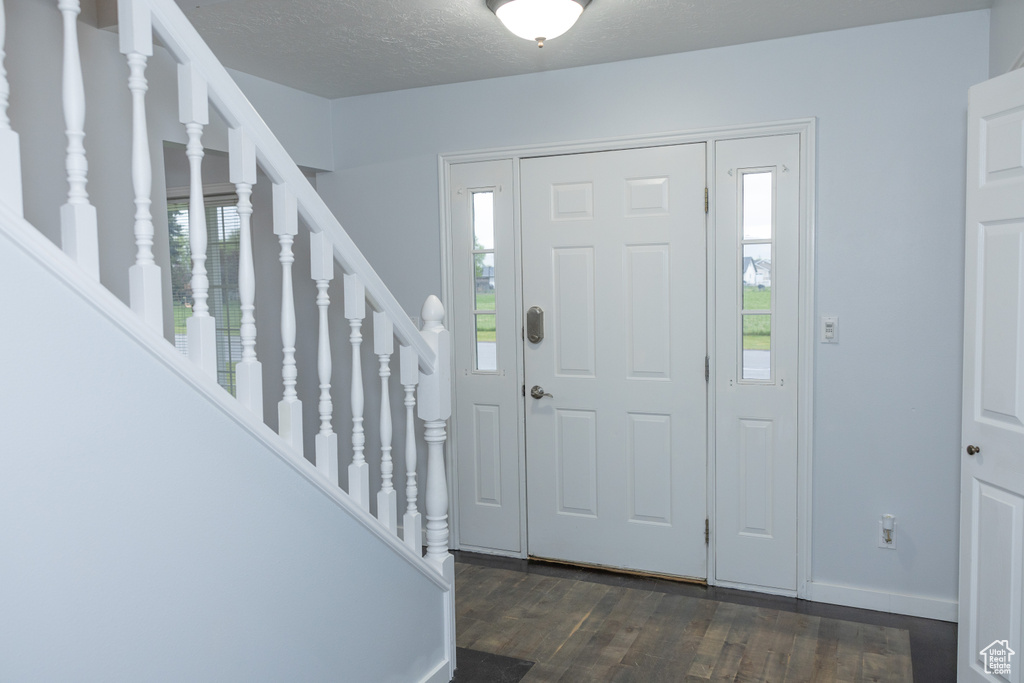 Entryway featuring dark wood finished floors, stairs, baseboards, and a textured ceiling