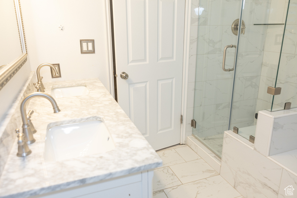 Bathroom featuring marble look tiles, a marble finish shower, and double vanity