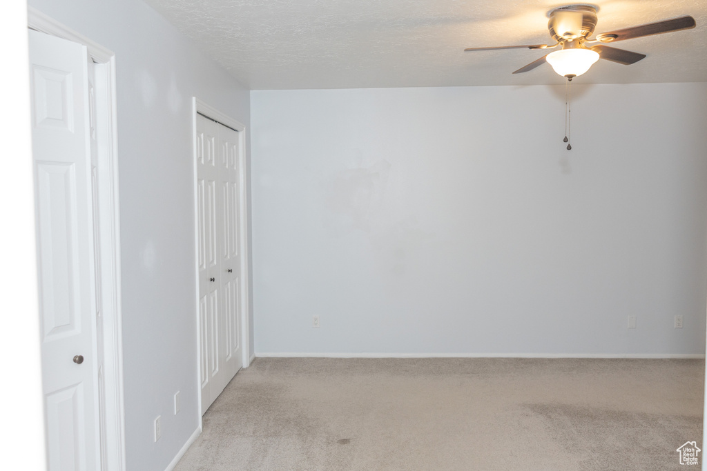 Empty room featuring ceiling fan, light colored carpet, and baseboards